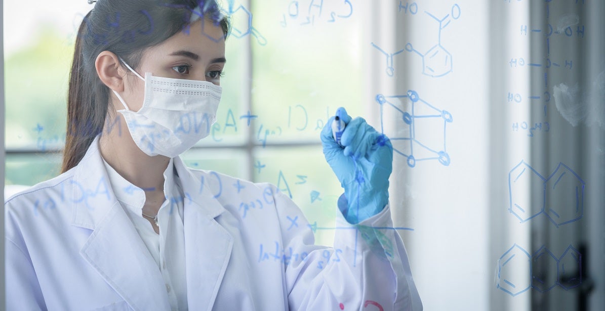 Young nurse reasercher in a lab, writing chemical formula