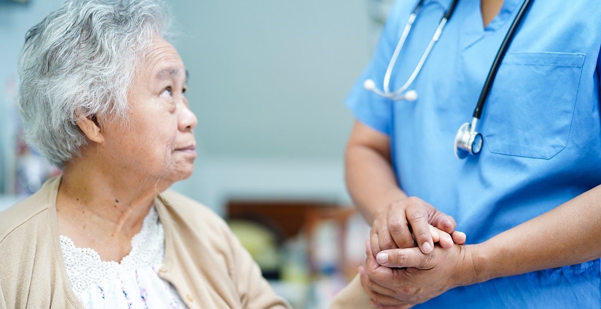 Psychiatric Nurse holding hand of an elderly female patient