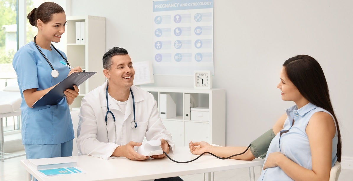 Doctor and nurse talking to a pregnant woman in their office